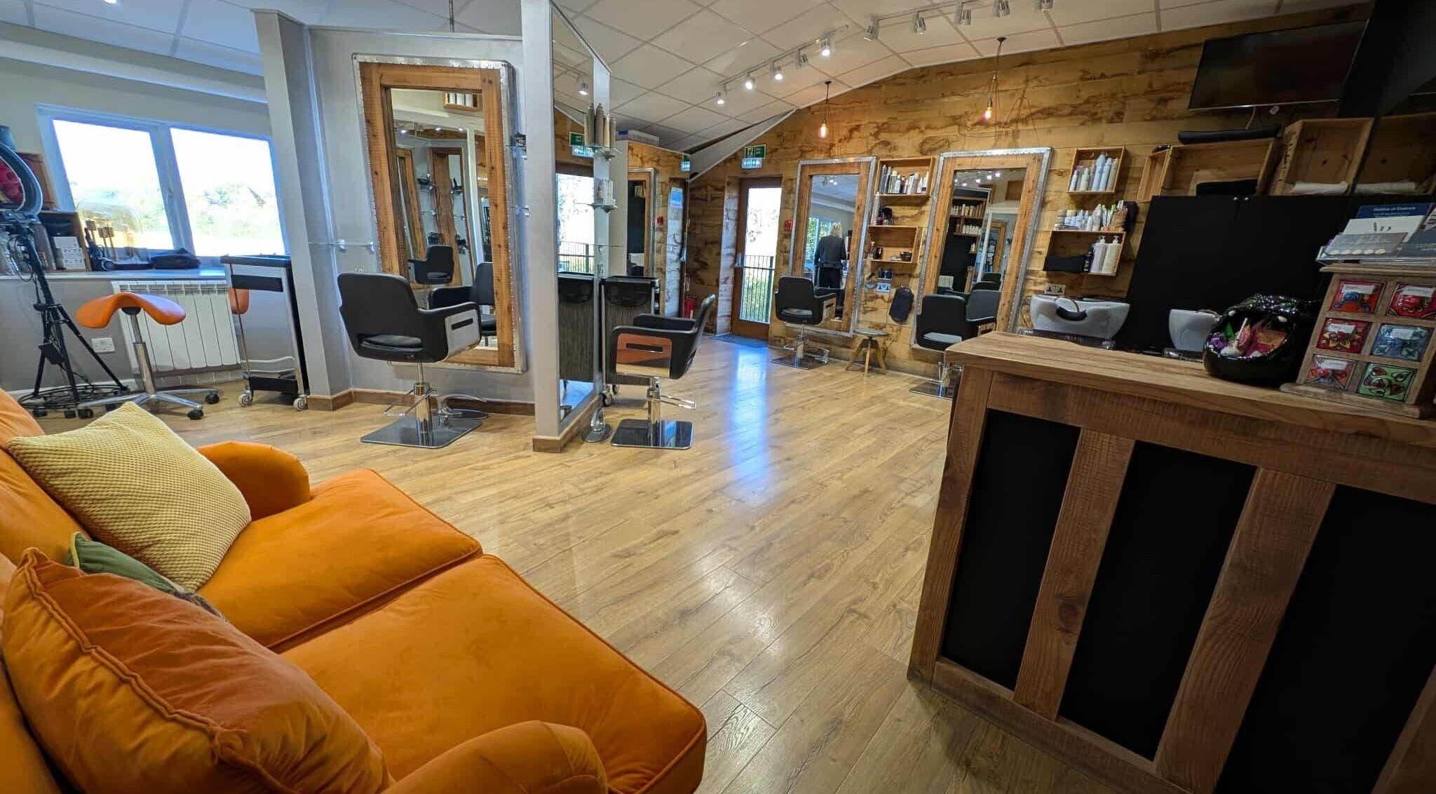 Stylish salon interior at Essence, Bourton-on-the-Water, England, GB with modern chairs and orange couch.