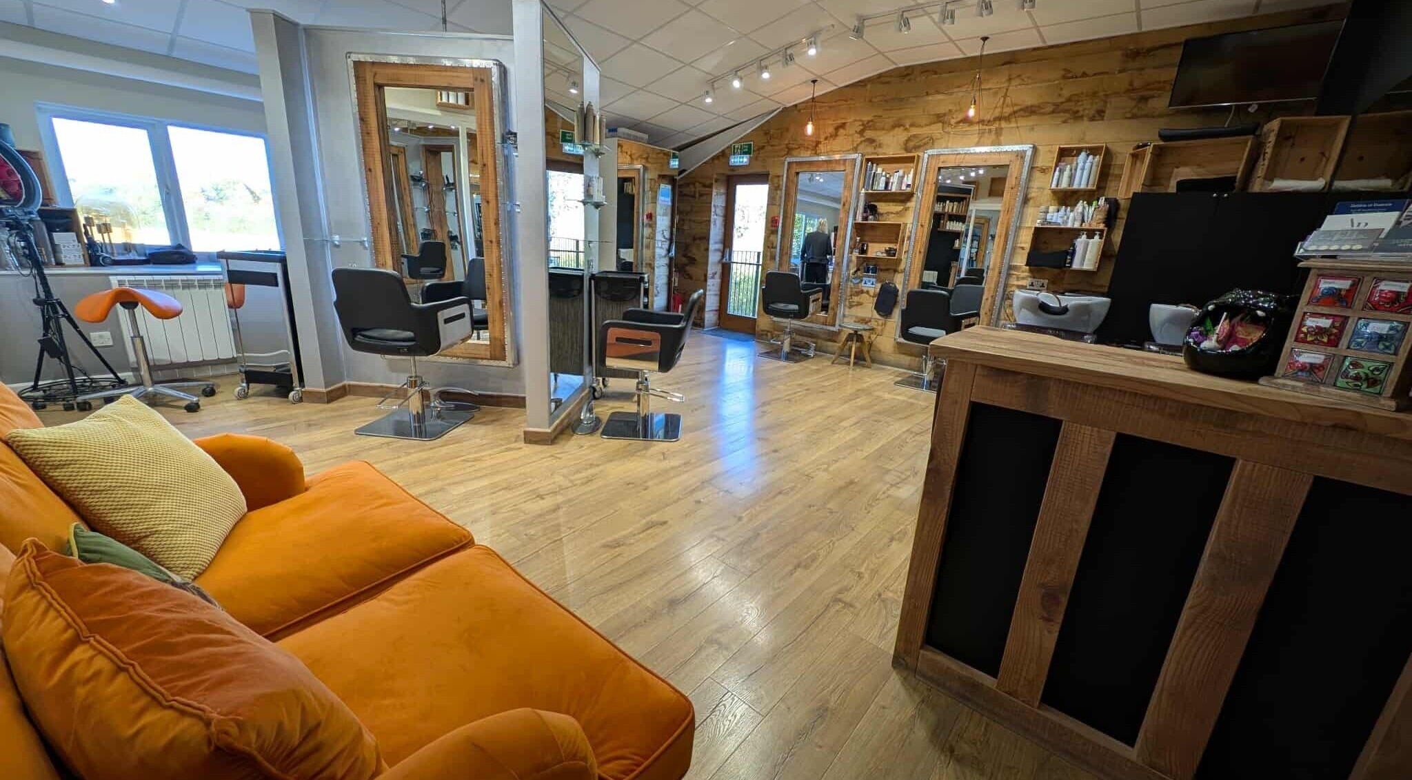 Stylish salon interior at Essence, Bourton-on-the-Water, England, GB with modern chairs and orange couch.