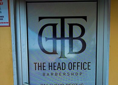 Entrance of The Head Office Barber Shop in Nassau, BS, featuring prominent logo on the door.