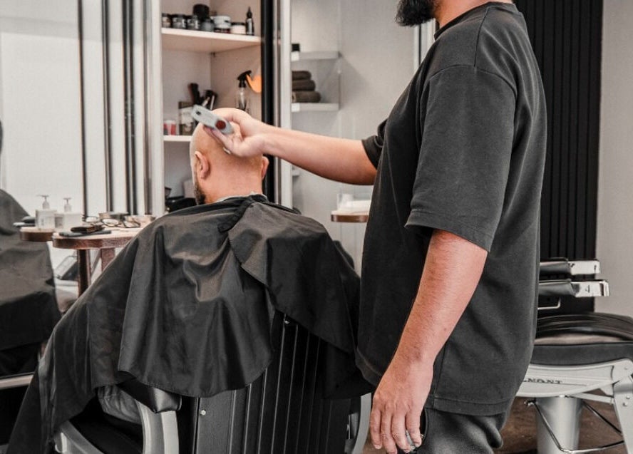 Barber styling man's hair at The BND - Barber Next Door, Abu Dhabi, AE.