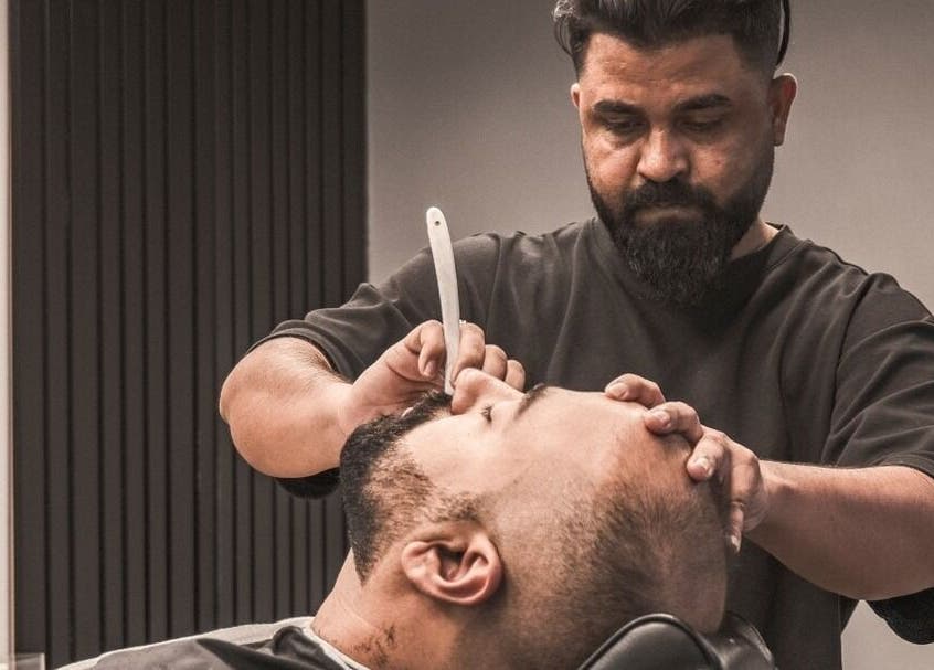 Expert barber providing a straight razor shave at The BND - Barber Next Door, Abu Dhabi, AE.