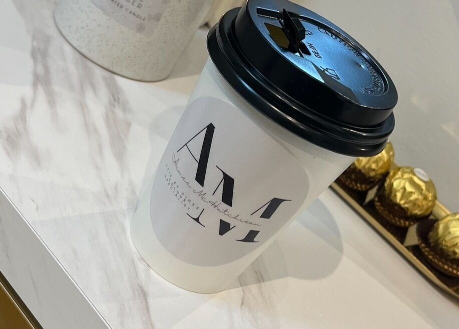 Luxury coffee cup at Hair by Aimee, Hatfield, England, GB, on a marble table with chocolates.