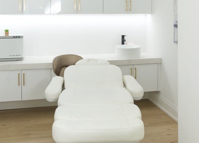 Calm, modern treatment room at Skin Cave Beauty in Mississauga, Ontario, CA with a white massage chair.