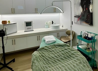 A cozy treatment room at Skin Cave Beauty in Mississauga, Ontario, CA with a green blanket on a bed.
