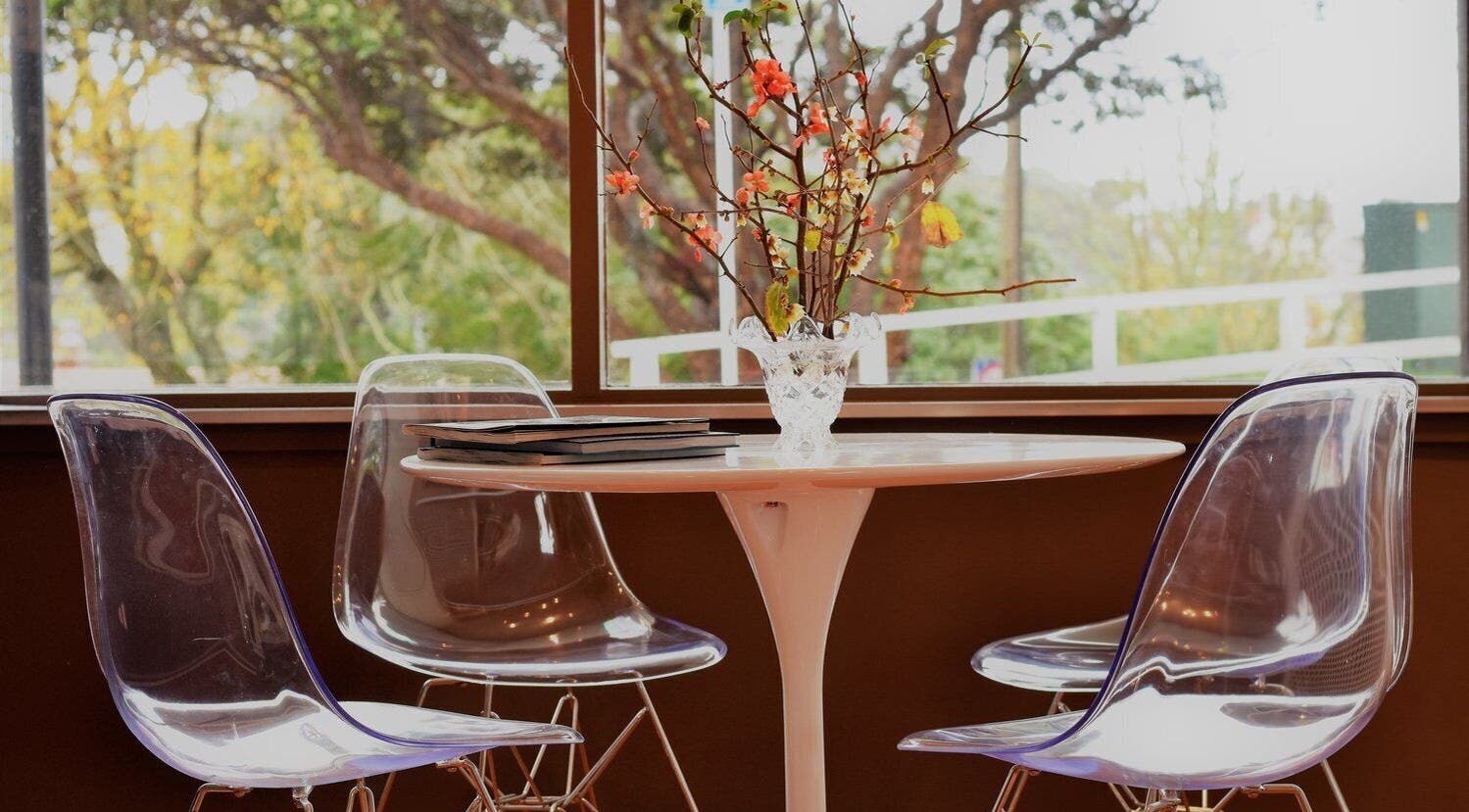 Chic seating area at David's Hairstylists, Wellington, NZ. Modern chairs around a round table with floral decor.