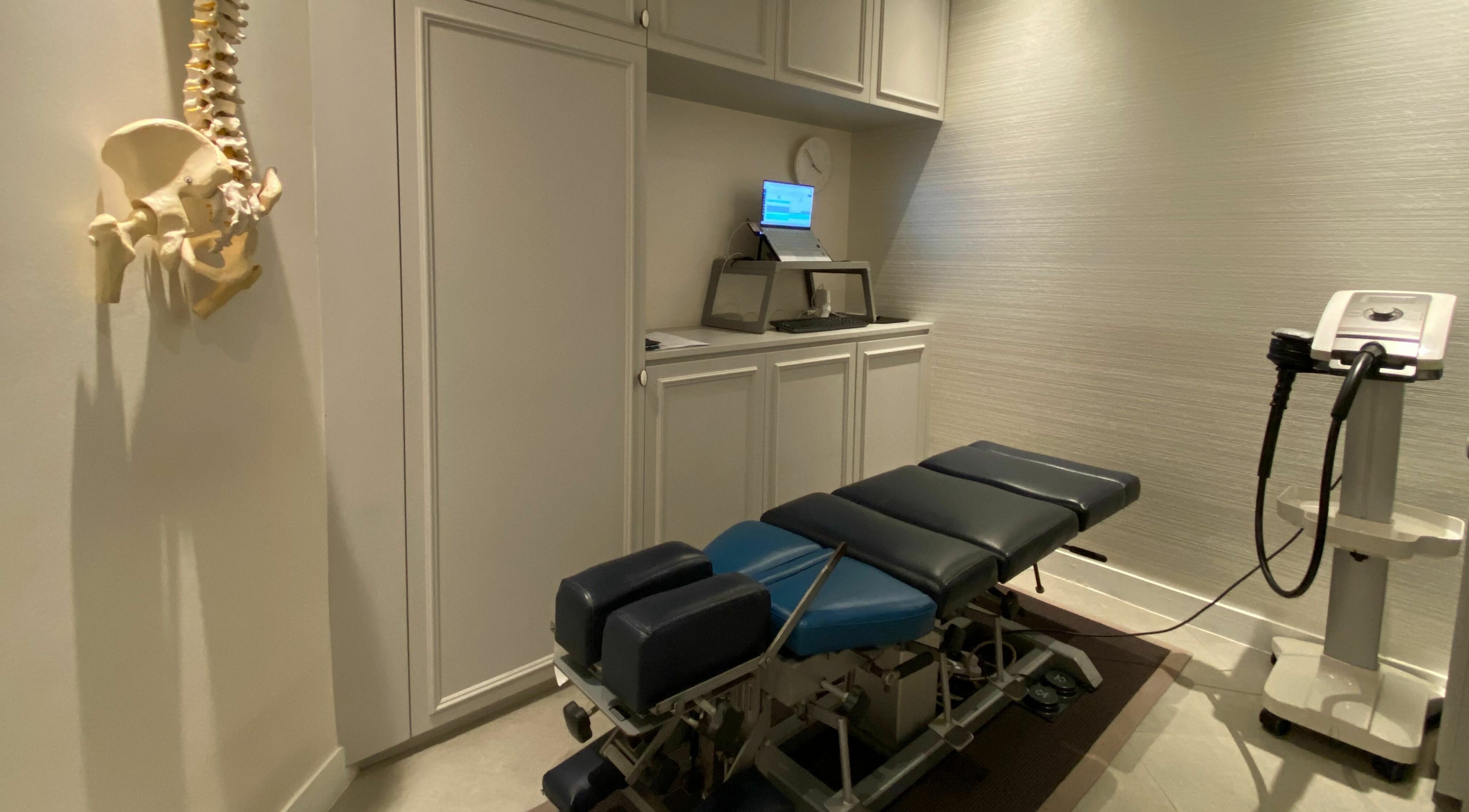 Chiropractic treatment room at Rin Spine Clinic, Hong Kong Island, HK, featuring an adjustable table and spine model.