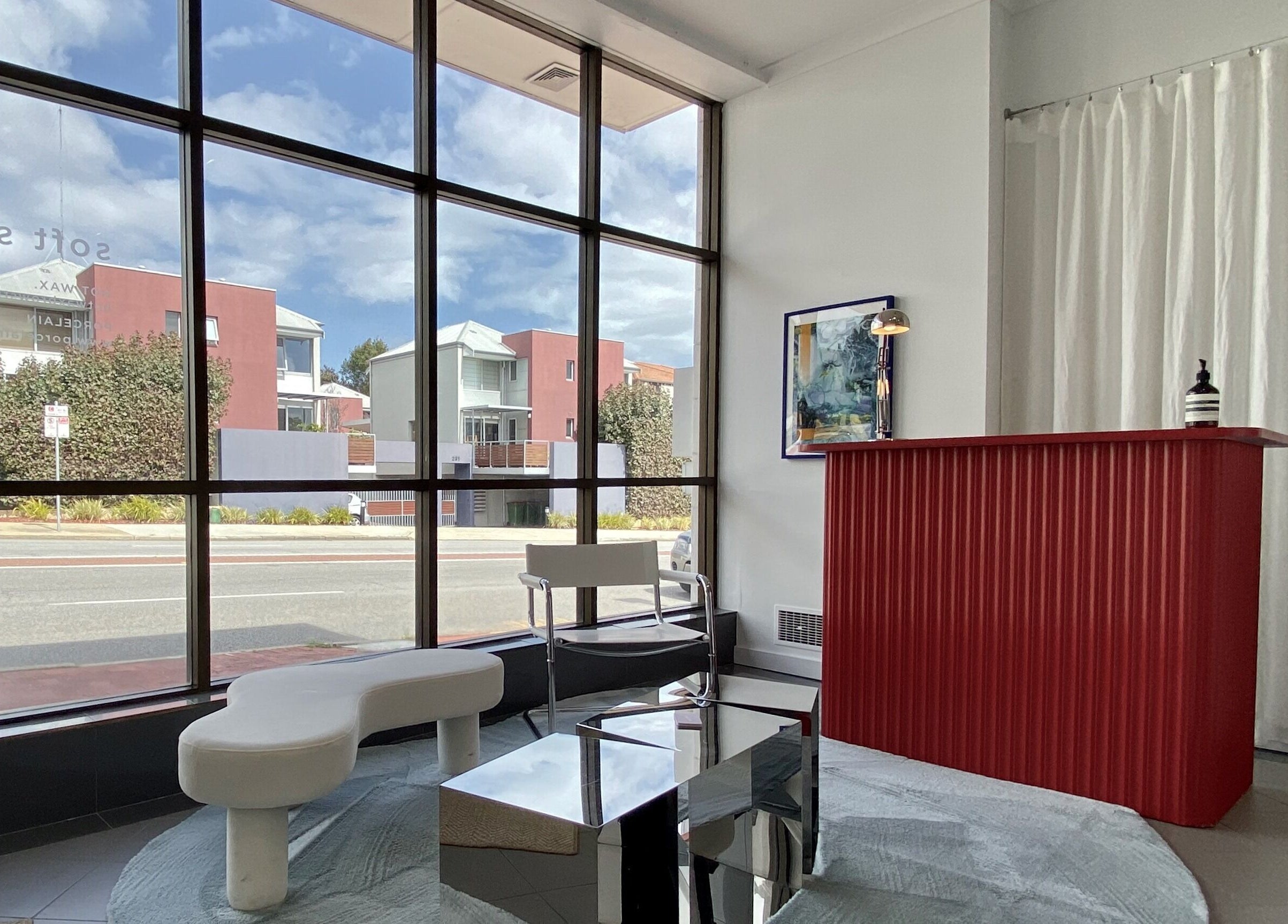 Stylish reception at Hot Wax, Wembley, Western Australia, AU with a modern red desk and large window view.