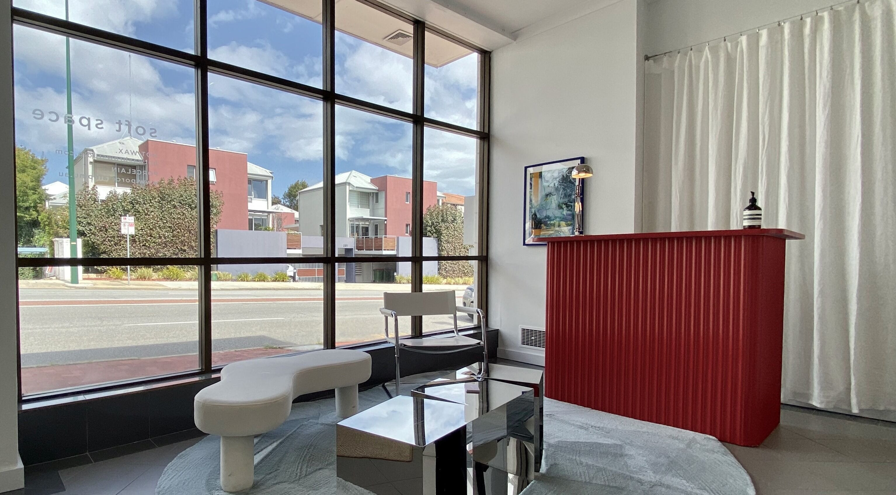 Stylish reception at Hot Wax, Wembley, Western Australia, AU with a modern red desk and large window view.