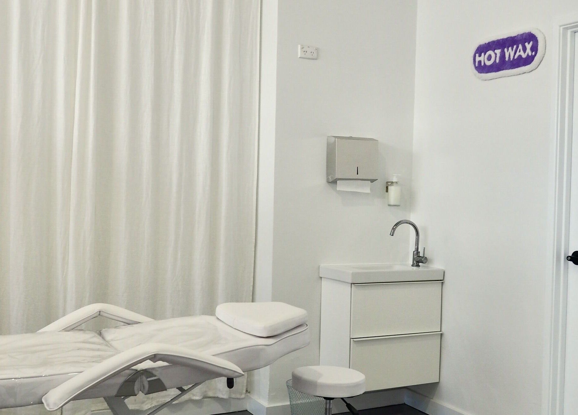Serene treatment room at Hot Wax, Wembley, Western Australia, AU, featuring a plush white bed and modern sink.