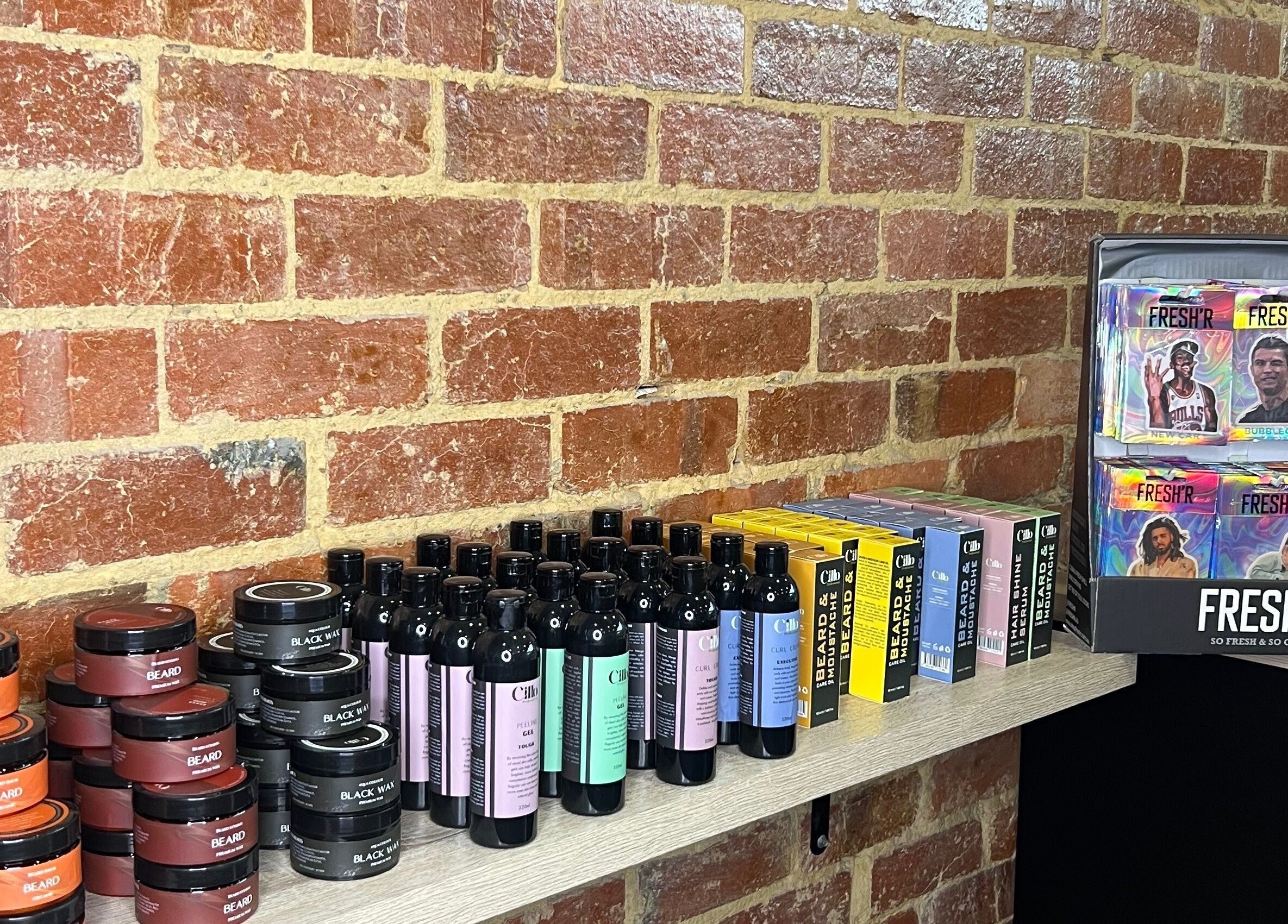 Array of grooming products at Barber Bros, Melbourne, Victoria, AU on a rustic brick wall shelf.