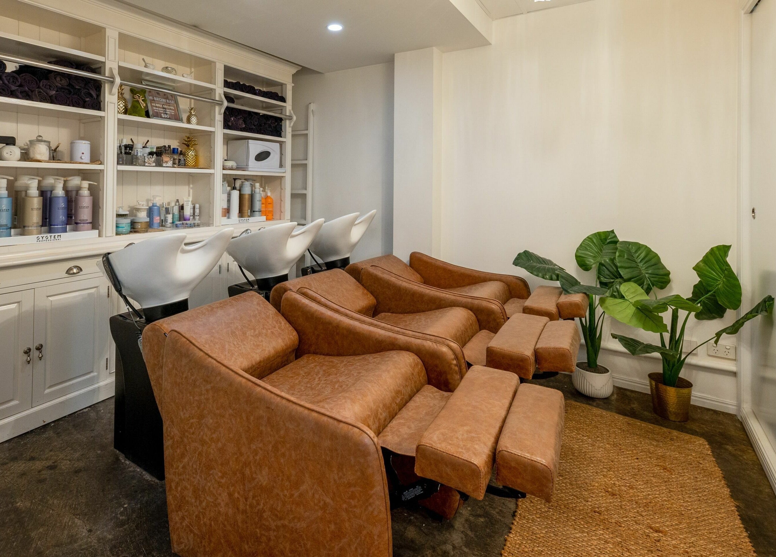 Luxurious salon wash stations at Style Mecha, Thorneside, Queensland, AU with brown chairs and product shelves.