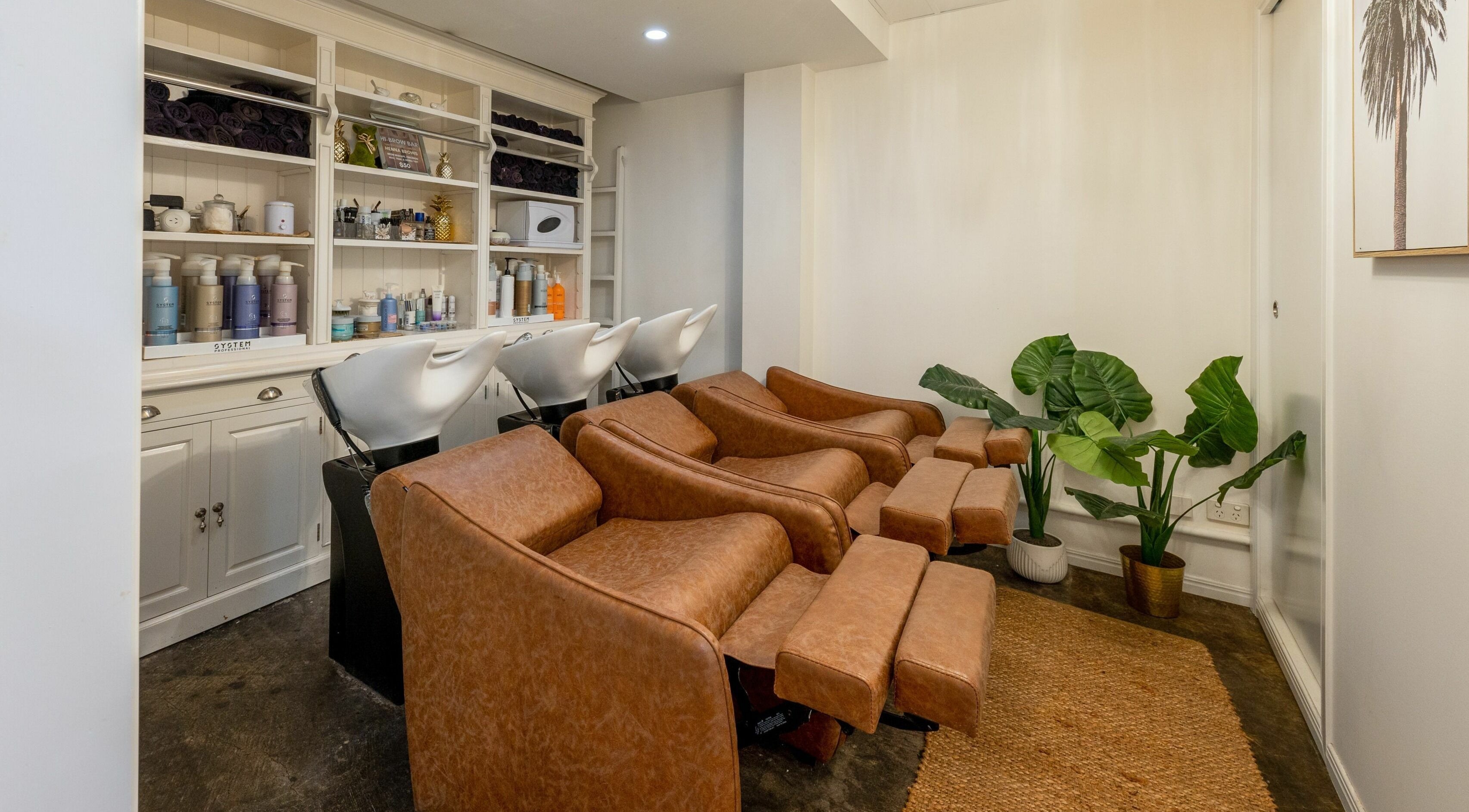 Luxurious salon wash stations at Style Mecha, Thorneside, Queensland, AU with brown chairs and product shelves.