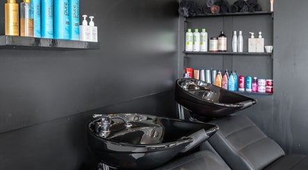 Wash stations at New Sensations Hairstyling in Melbourne, Victoria, AU, featuring sleek black basins and stocked shelves.