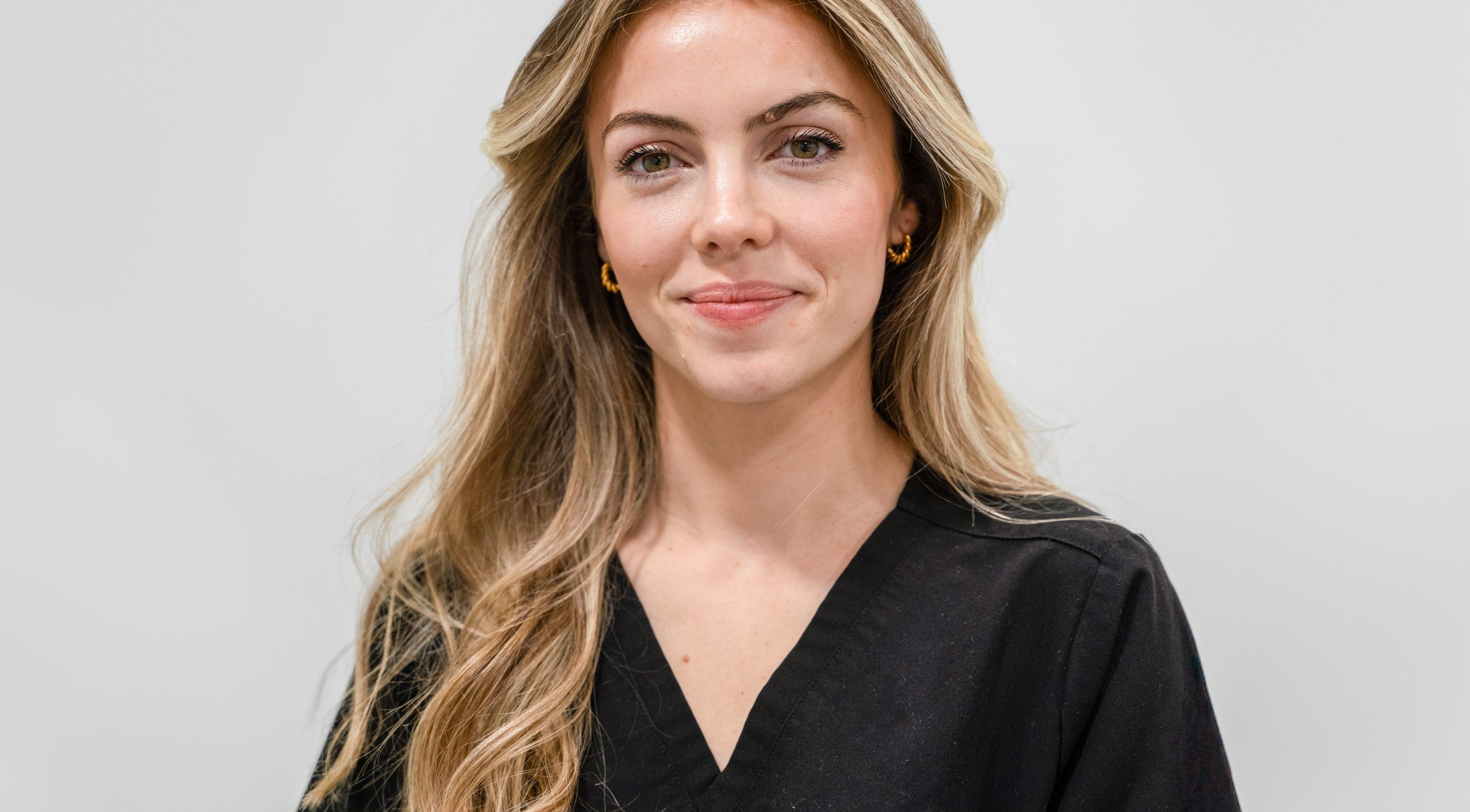 Staff member at Dr Wells Clinic - Medical Aesthetics & Wellness, London, England, GB, smiling in uniform.