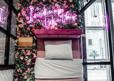 Luxurious treatment bed at We Nails Trident Grand Residence, Dubai, AE, with neon lights and floral decor.