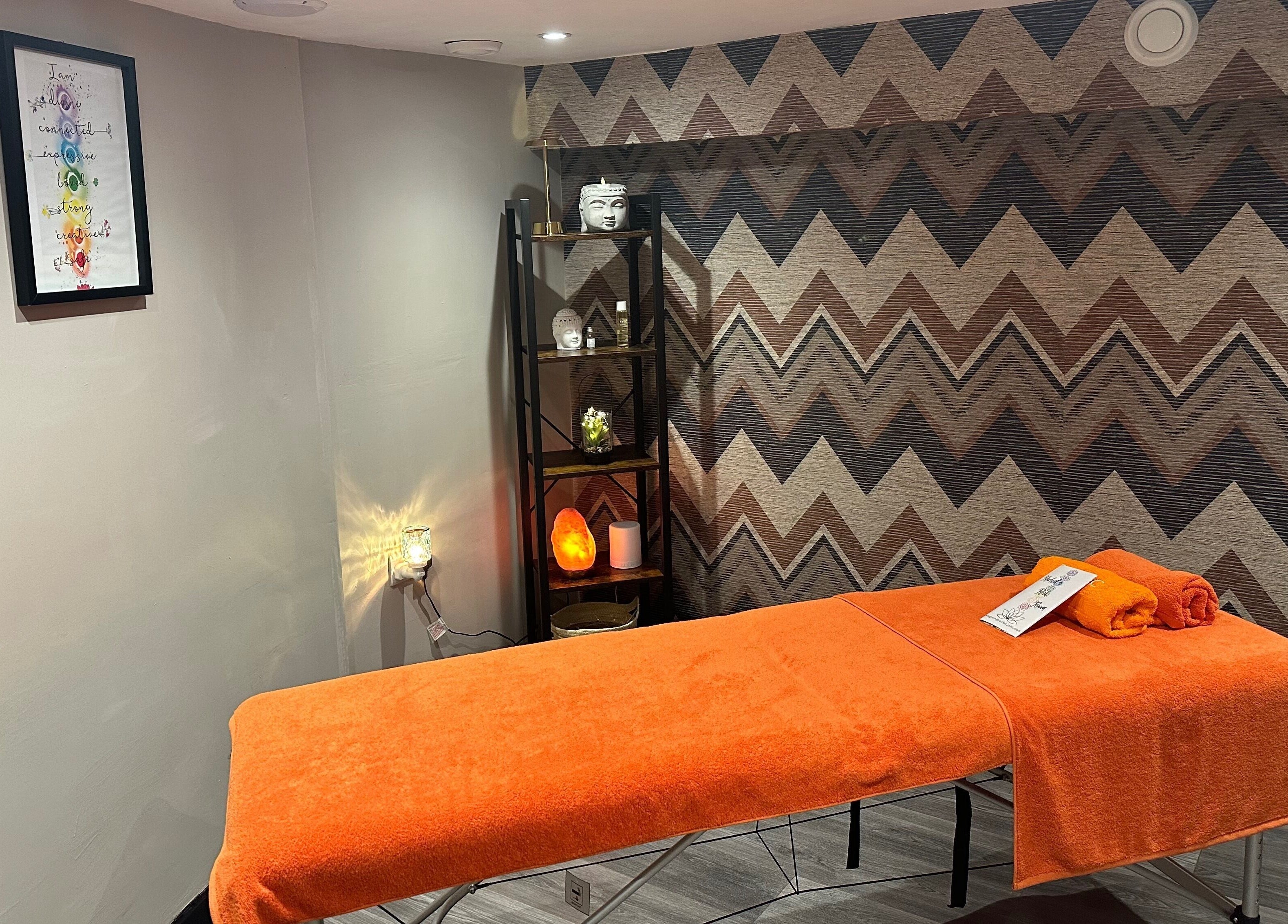 Relaxing massage room at The Elite Retreat, Biddulph, SOT, England, GB, with orange decor and calming ambiance.