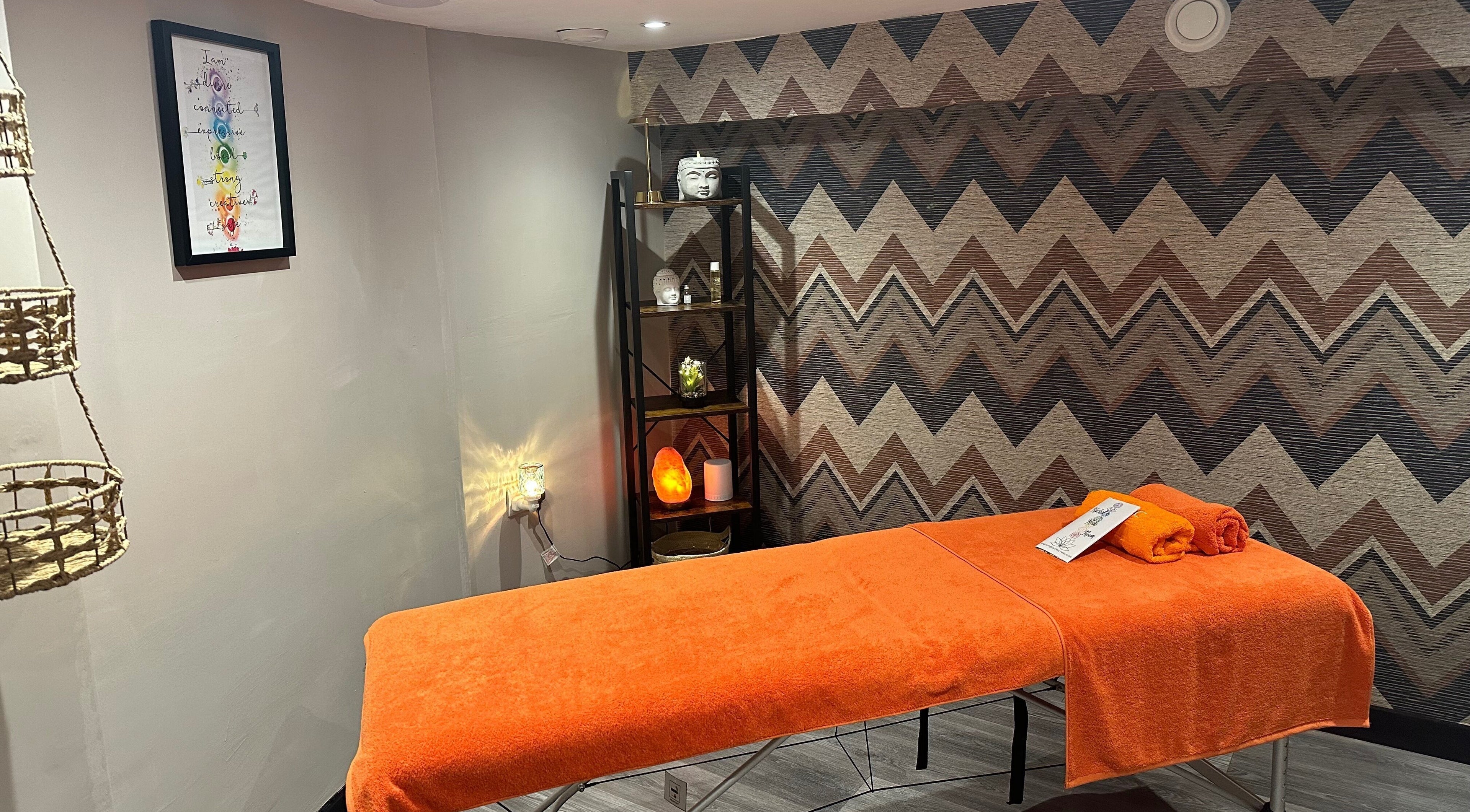 Relaxing massage room at The Elite Retreat, Biddulph, SOT, England, GB, with orange decor and calming ambiance.