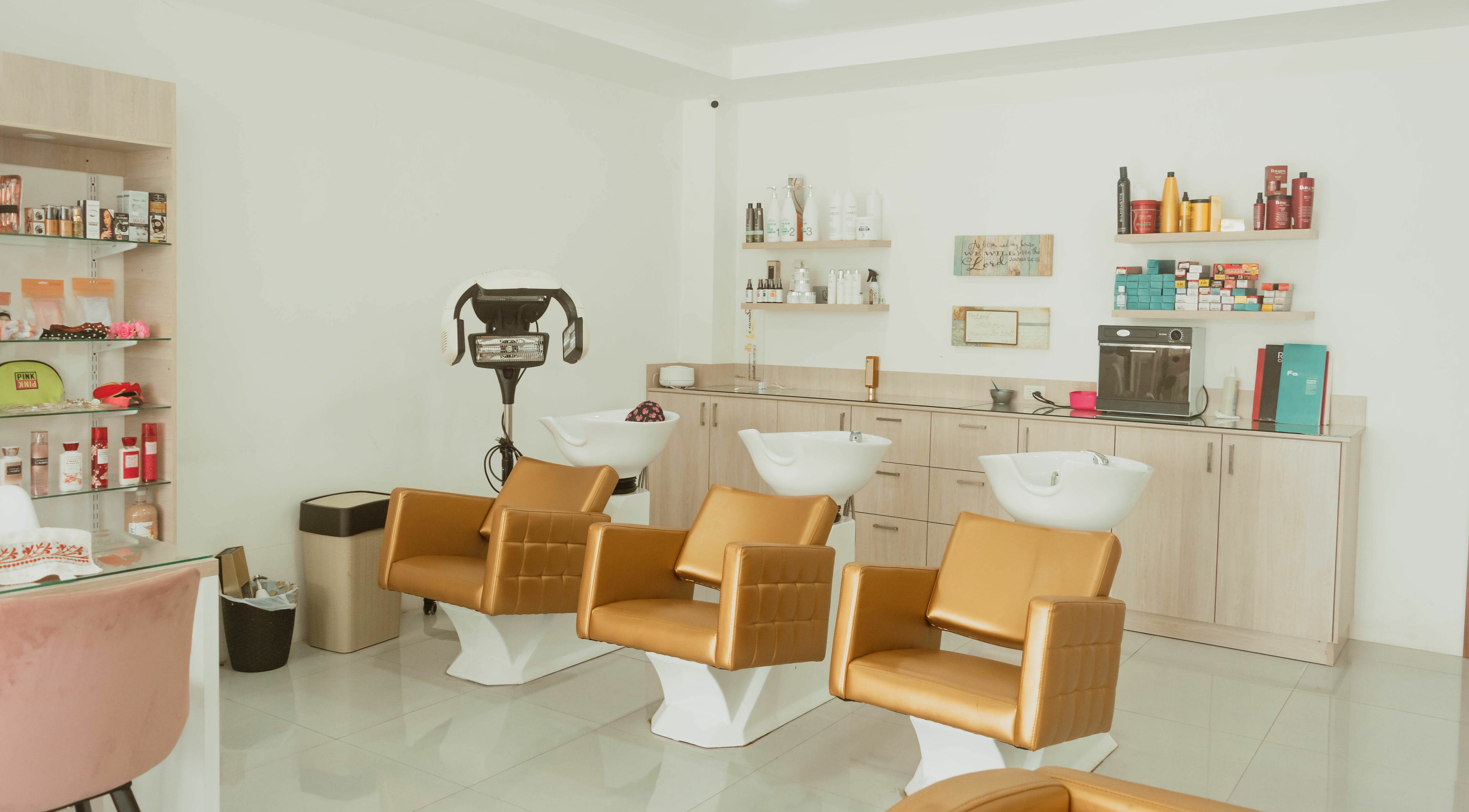 Interior del salón La Casa del Estilista en Esmeraldas, EC, con sillas doradas y productos de belleza en estantes.