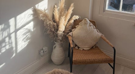 Cozy corner at Face Co Beauty and Aesthetics, Taunton, England, GB with woven chair, pampas grass, and soft lighting.