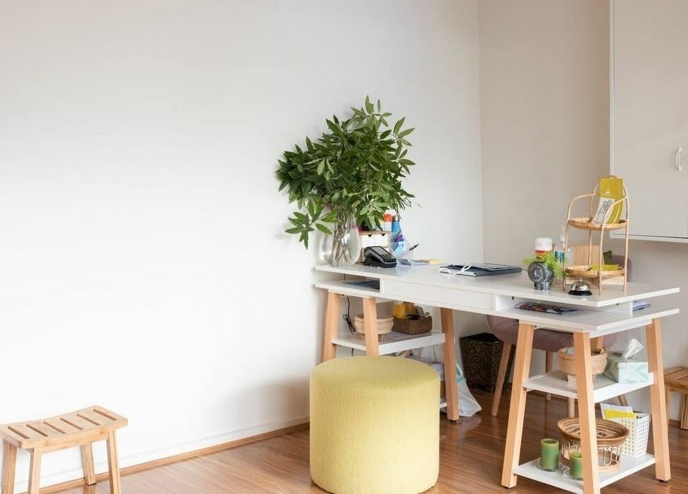 Cozy workspace at The Massage Studio in Melbourne, Victoria, AU with a desk, stool, and indoor plant.