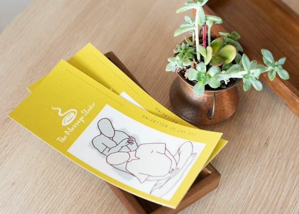 Brochures of The Massage Studio with a plant on a wooden table in Melbourne, Victoria, AU.