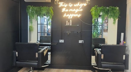 Stylish salon chairs and mirrors at THE GLOSS, Lowestoft, England, GB with neon sign and greenery.