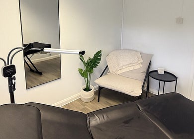 Modern treatment room at Tweak Clinic in Peterborough, England, GB, featuring a sleek bed and cozy chair.