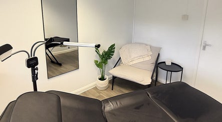 Modern treatment room at Tweak Clinic in Peterborough, England, GB, featuring a sleek bed and cozy chair.
