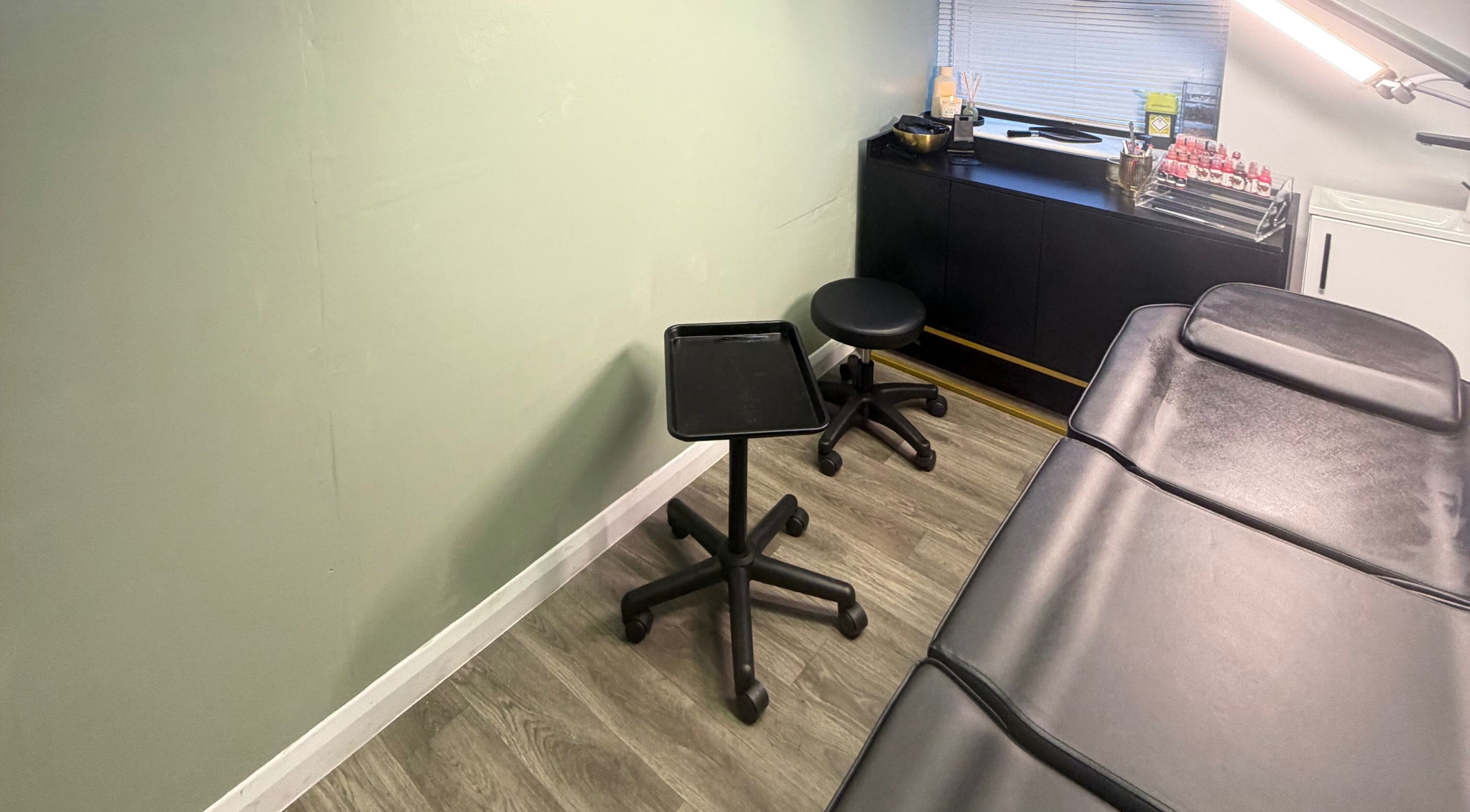 Treatment room at Tweak Clinic, Peterborough, England, featuring a black chair and table.