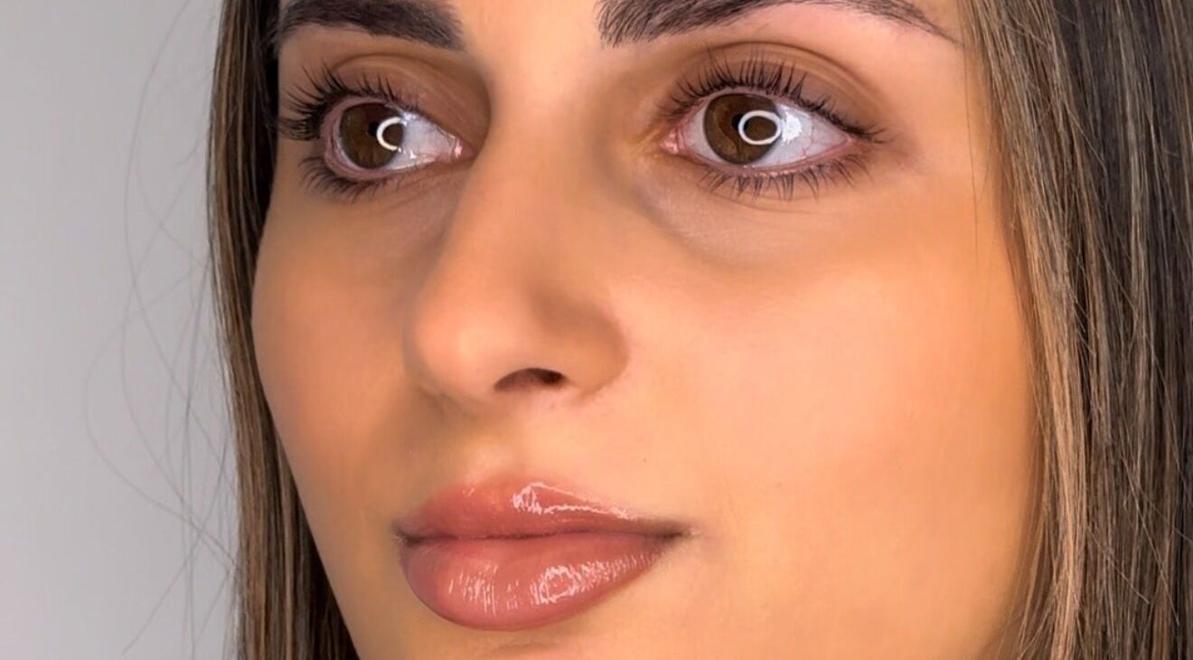 Close-up of a woman with radiant skin and glossy lips at Sneaky Wink in Melbourne, Victoria, AU.