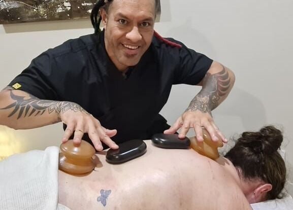 Therapist performing hot stone massage at Mana Physiques, South Toowoomba, Queensland, AU.