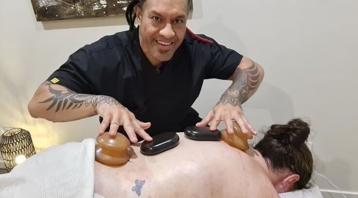 Therapist performing hot stone massage at Mana Physiques, South Toowoomba, Queensland, AU.