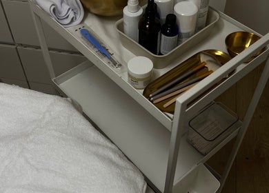 Beauty supplies at FIBA Clinic, Leeds, England, GB. Includes brushes, bottles, and a towel on a white trolley.