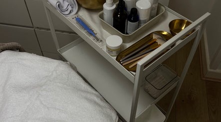 Beauty supplies at FIBA Clinic, Leeds, England, GB. Includes brushes, bottles, and a towel on a white trolley.