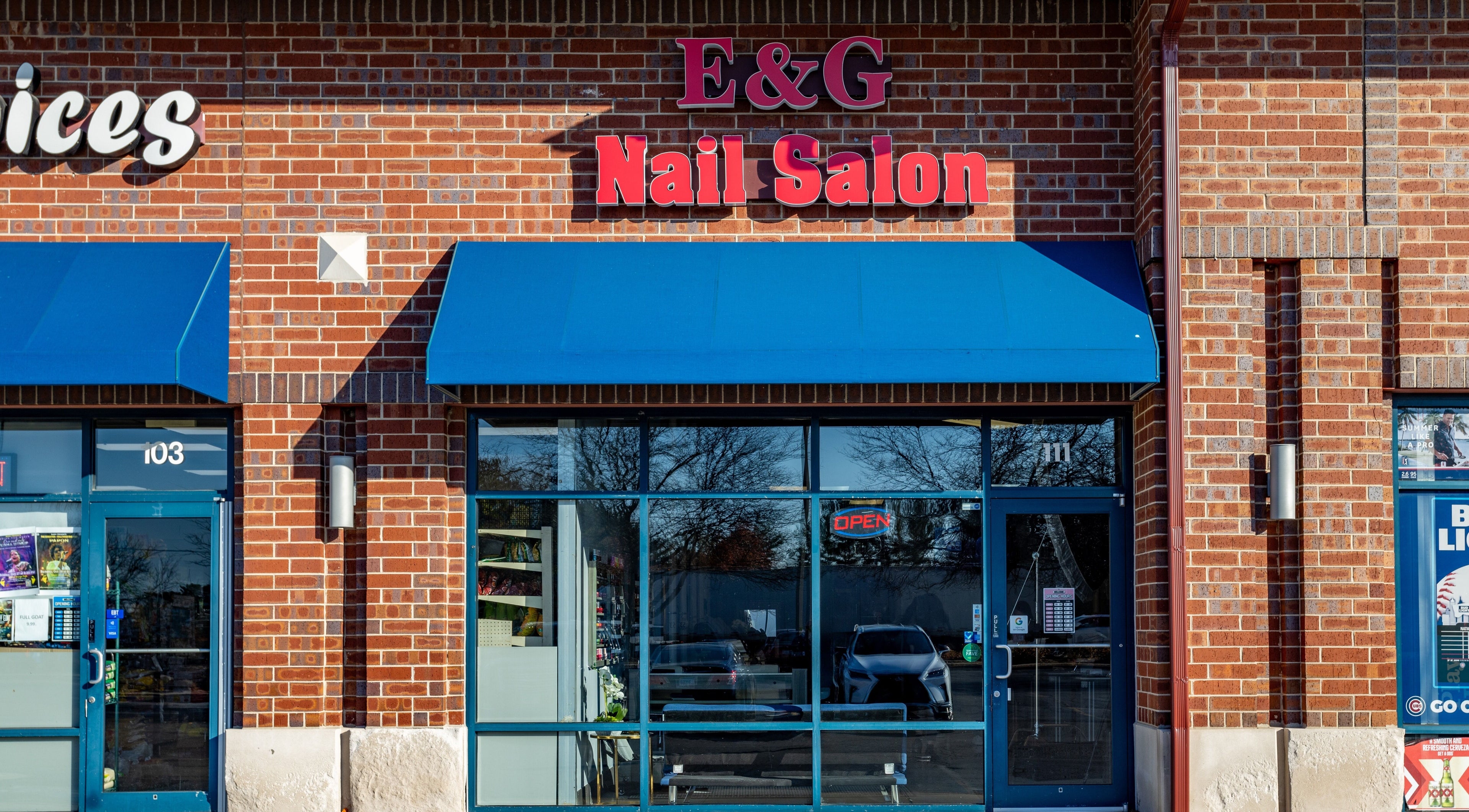 Front view of EG Nails & Spa in Naperville, Illinois, US with a brick exterior and blue awnings.