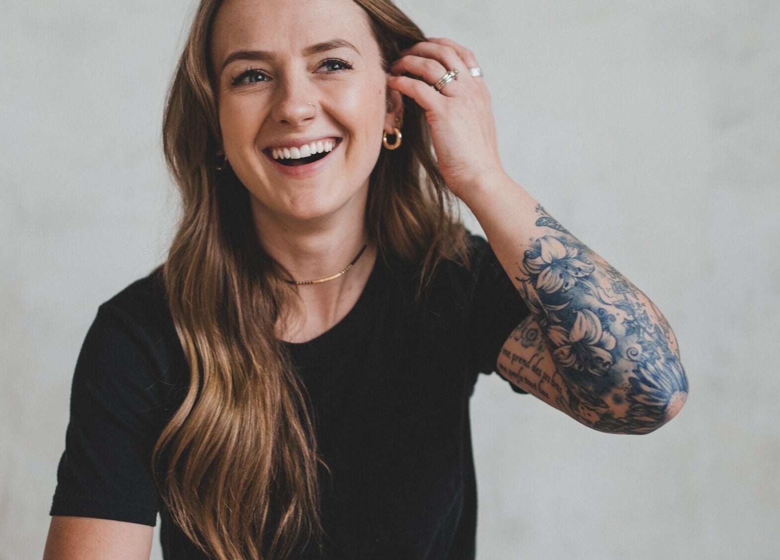 Smiling woman with tattooed arm at Pura Vida Salon, Livingston, Montana, US.