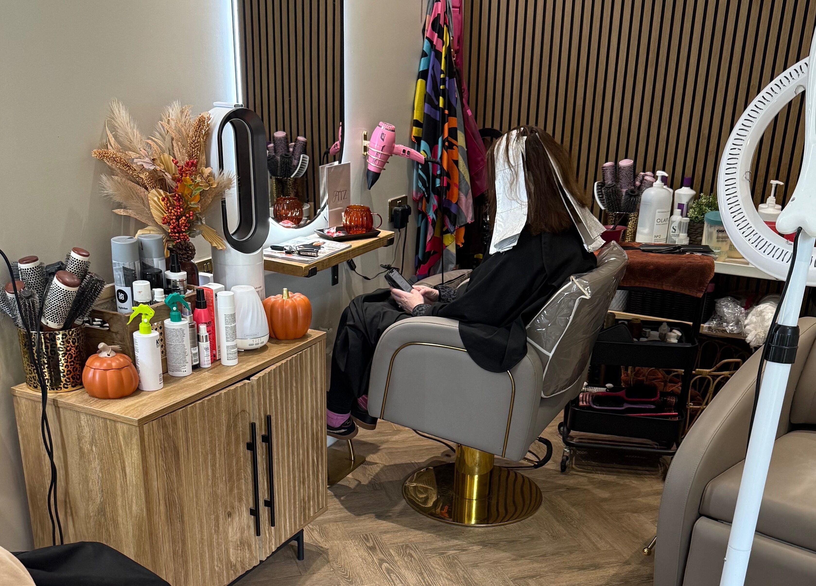 Client in styling chair at Kate Fitzpatrick Hair, Deeside, Wales, GB, surrounded by beauty products.