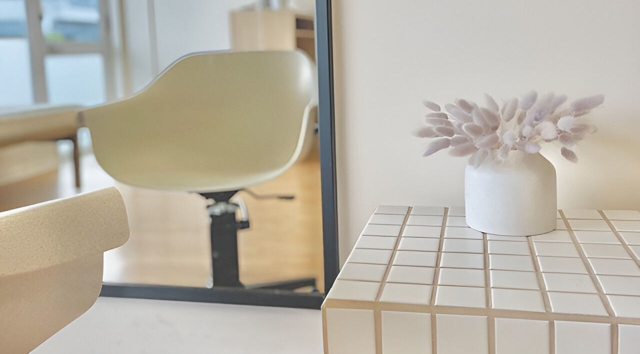 Elegant seating area in Muse Hair Studio, Bay of Plenty, NZ, with chic decor and a modern chair.