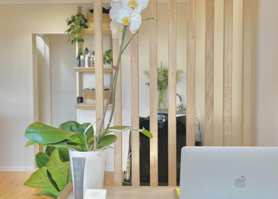 Reception area of Muse Hair Studio in Bay of Plenty, NZ with laptop and orchid decor.