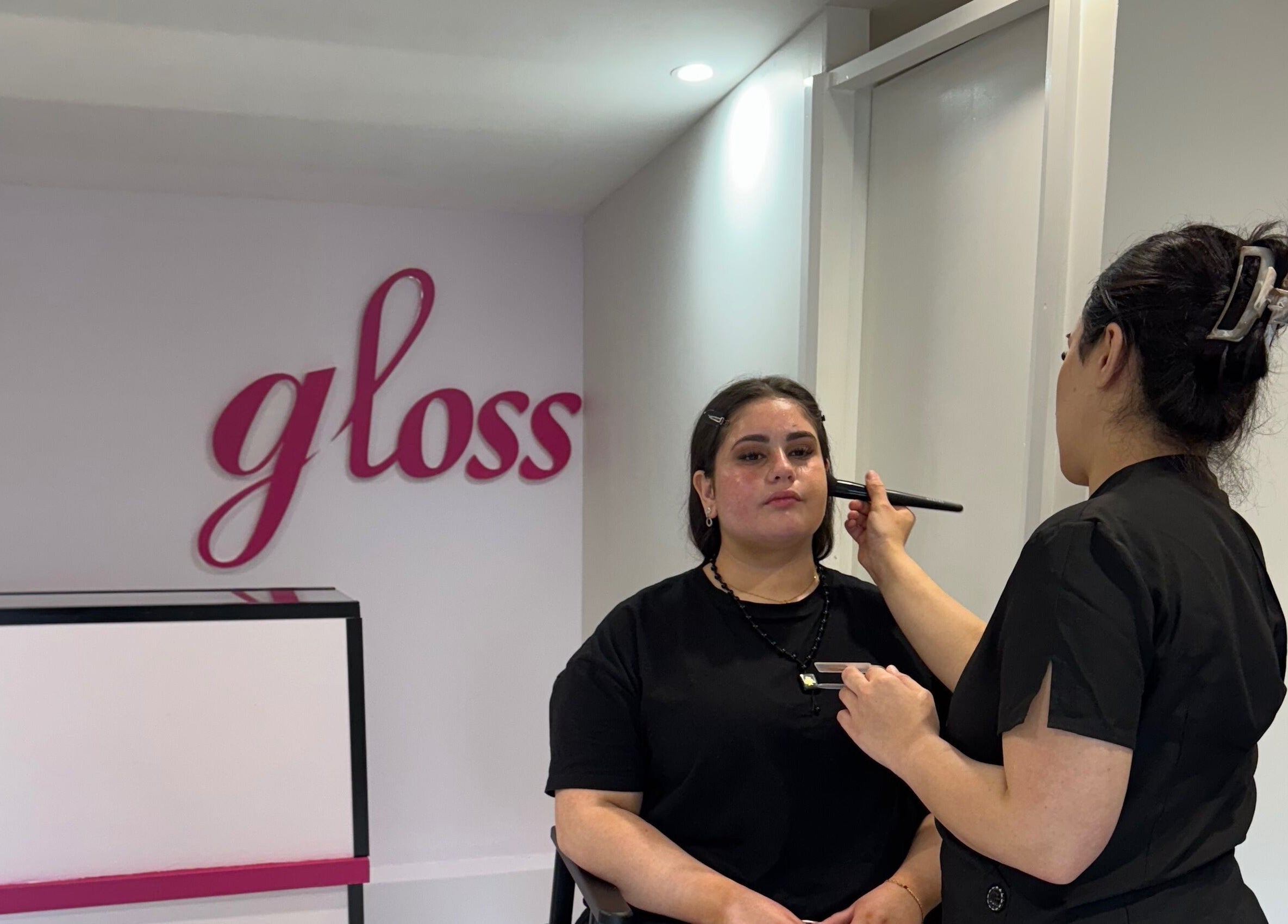 Makeup artist at Gloss Beauty Salon in Prestons, New South Wales, AU, applying makeup to client.