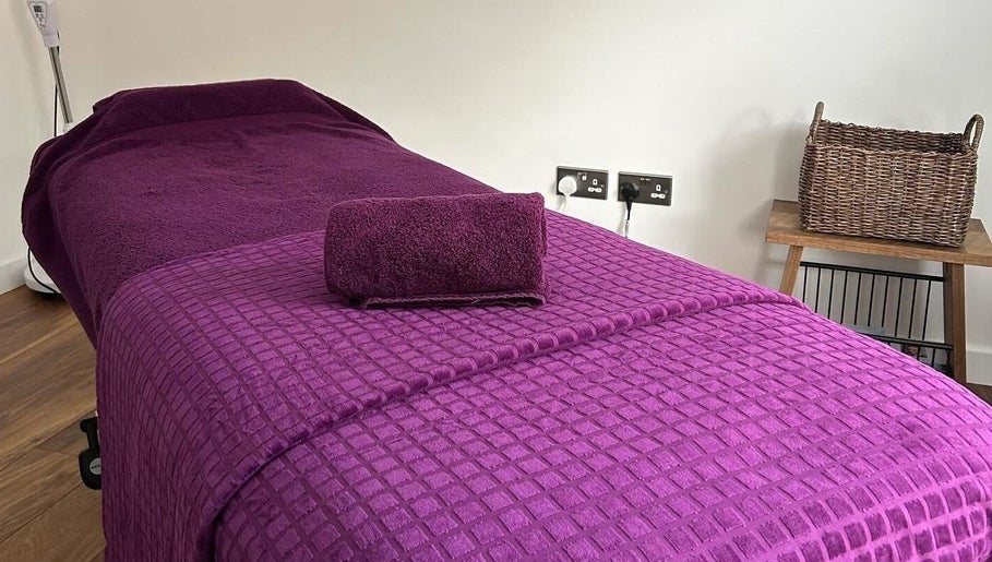 Relaxing massage table setup in Orchard Holistic Therapy, Waterlooville, England, GB with plush purple linens.