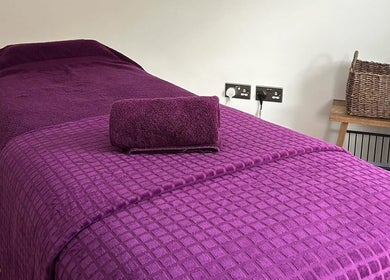 Relaxing massage table setup in Orchard Holistic Therapy, Waterlooville, England, GB with plush purple linens.