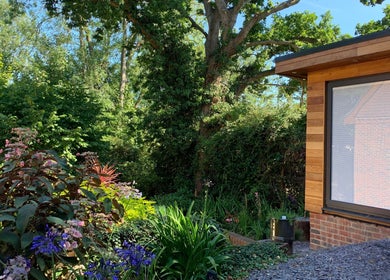 Lush garden view at Orchard Holistic Therapy, Waterlooville, England, GB, showcasing wooden building exterior.