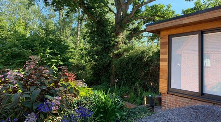 Lush garden view at Orchard Holistic Therapy, Waterlooville, England, GB, showcasing wooden building exterior.