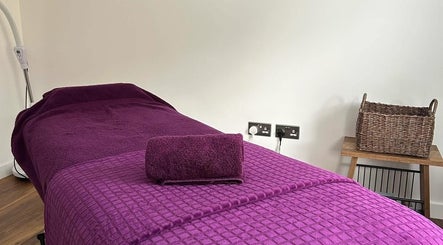 Comfortable massage table at Orchard Holistic Therapy, Waterlooville, England, GB, prepared with purple linens.