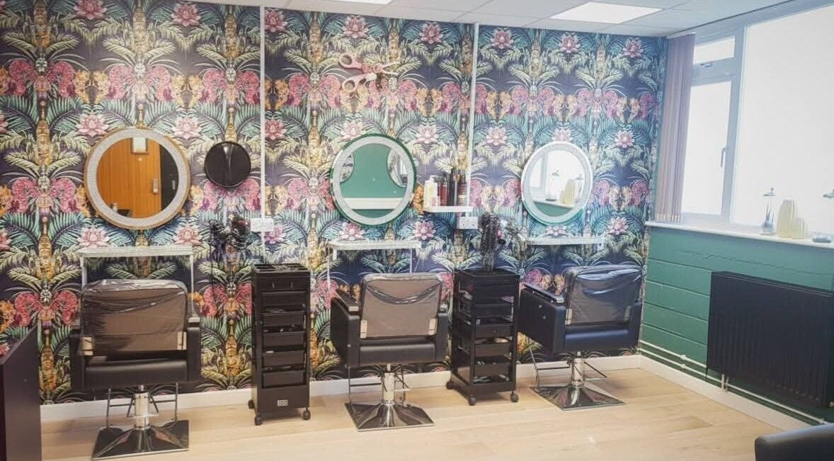 Amore salon interior in St Austell, England, GB with vibrant floral wallpaper and modern styling chairs.