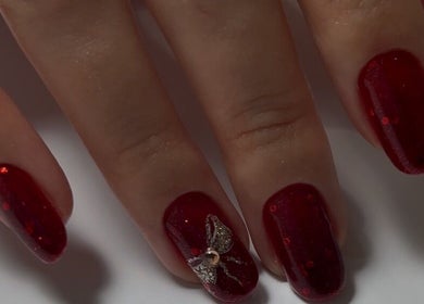 Red glitter nails with a silver bow at Silvia Vasiliu Nails, STOKE-ON-TRENT, England, GB.
