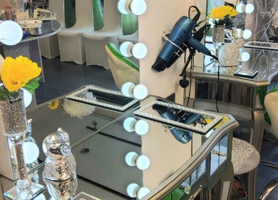 Elegant salon vanity at Need a Makeover Hair, Dudley, England, GB, with flowers and mirror lights.