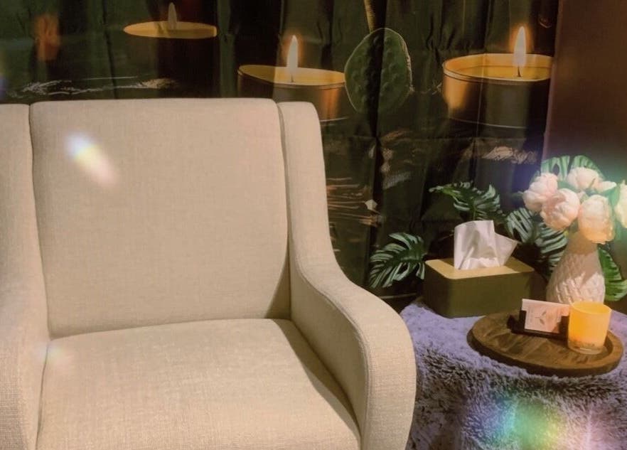 Cozy chair with flowers and candles at CamelliasBodyMassage, Christchurch, NZ for a peaceful ambiance.