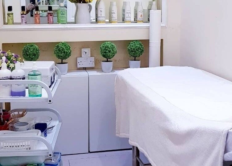 Calming treatment room at Absolute Joy Spa, London, England, GB showcasing skincare products and cozy setup.